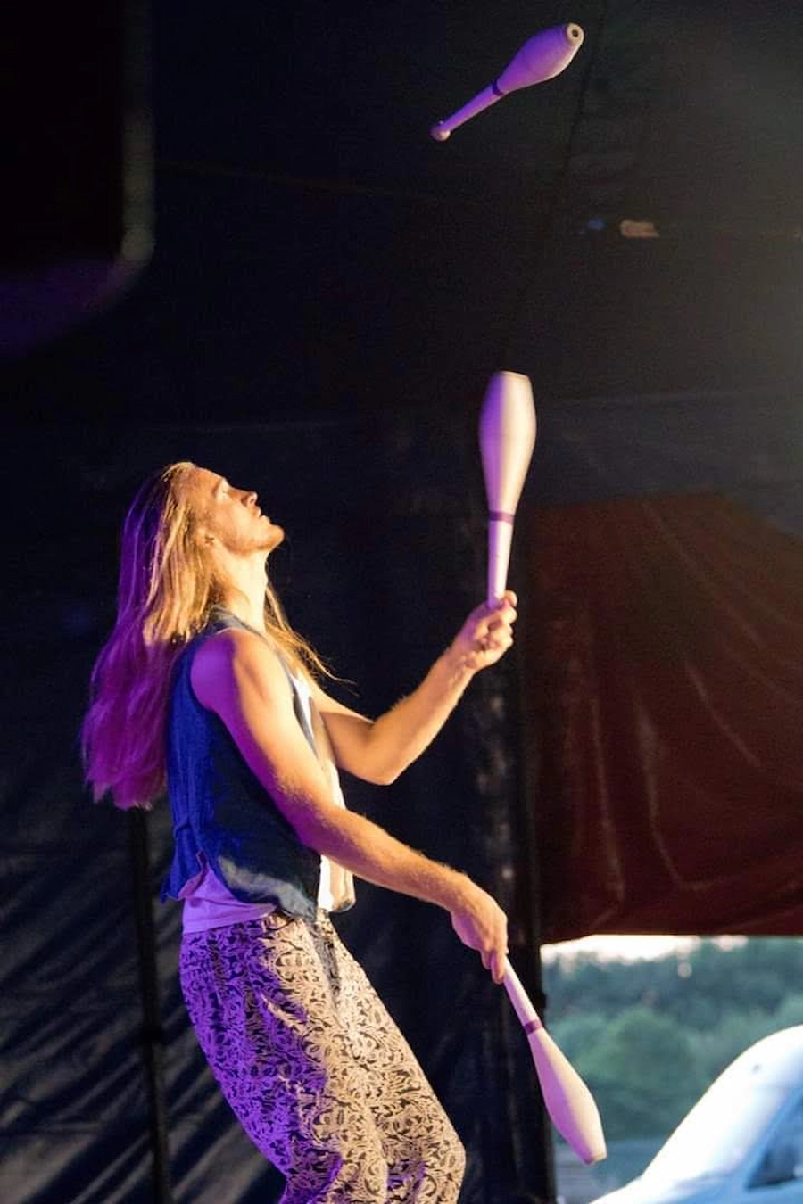 Juggler performing with pins in a circus tent