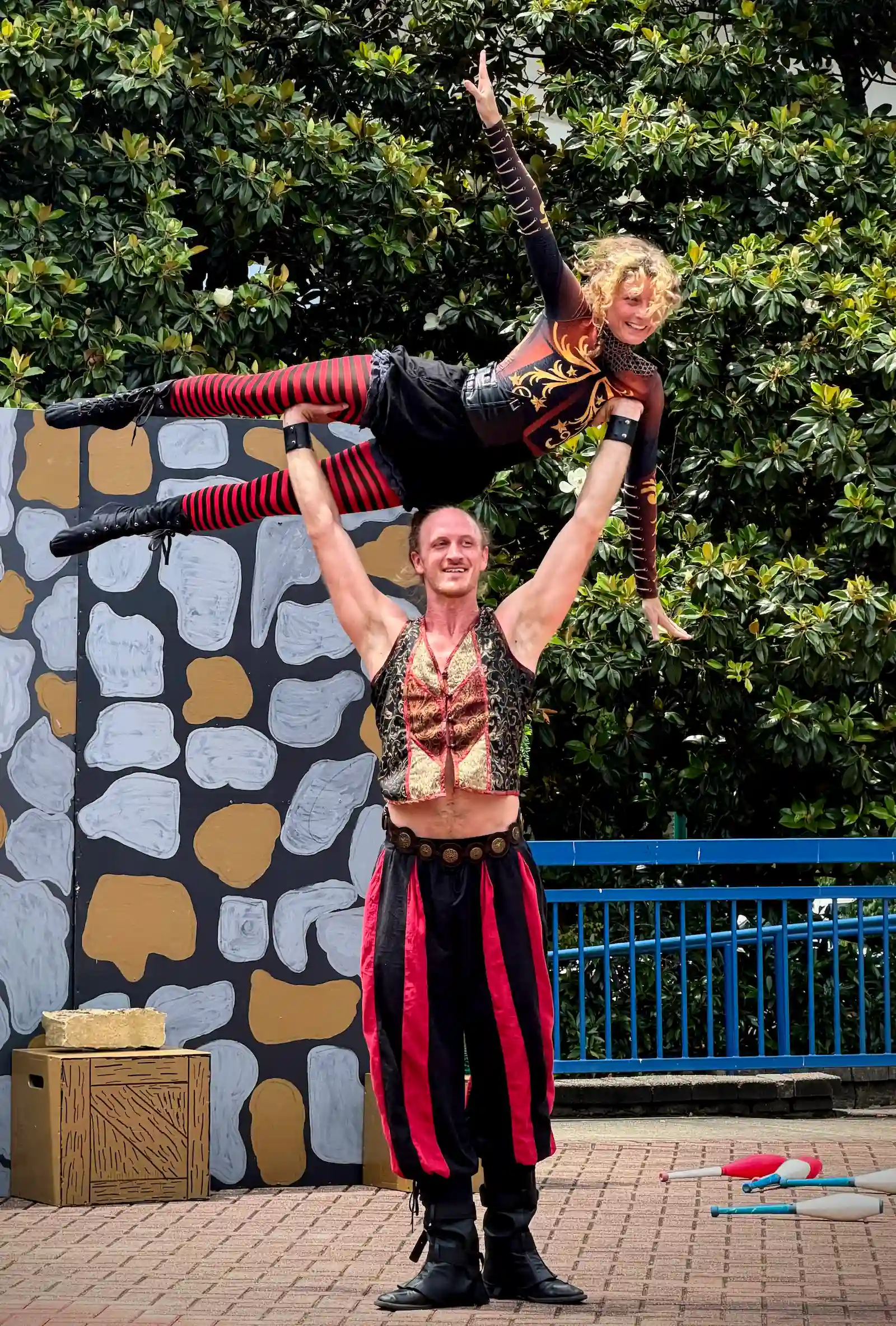 Acrobat holding flyer horizontally over head in renaissance clothes on stage