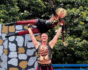 Acrobat holding flyer horizontally over head in renaissance clothes on stage