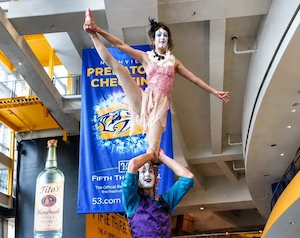 Clown acrobats with flyer standing on shoulders of base holding one leg straight up