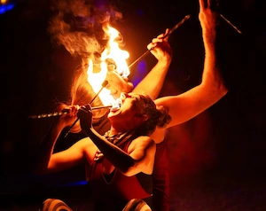 Fire performers eating fire sitting on ground back to back
