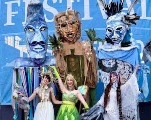 Three giant wearable elemental puppets and matching ground characters at a festival