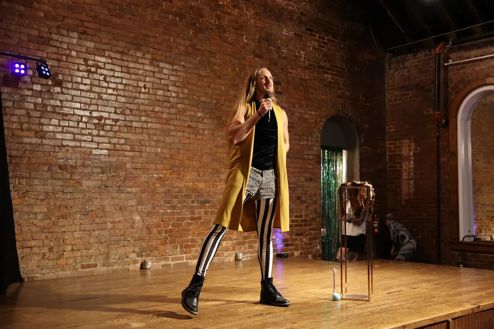 Logan talking on microphone hosting a circus show wearing black and white stripes