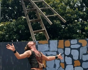Renaissance performer balancing large wooden ladder on face on a stage