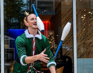 Juggler dressed as an elf performing for an audience