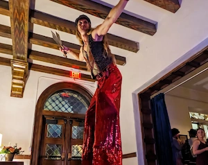 Stilt walker in red sequin pants at event juggling knives